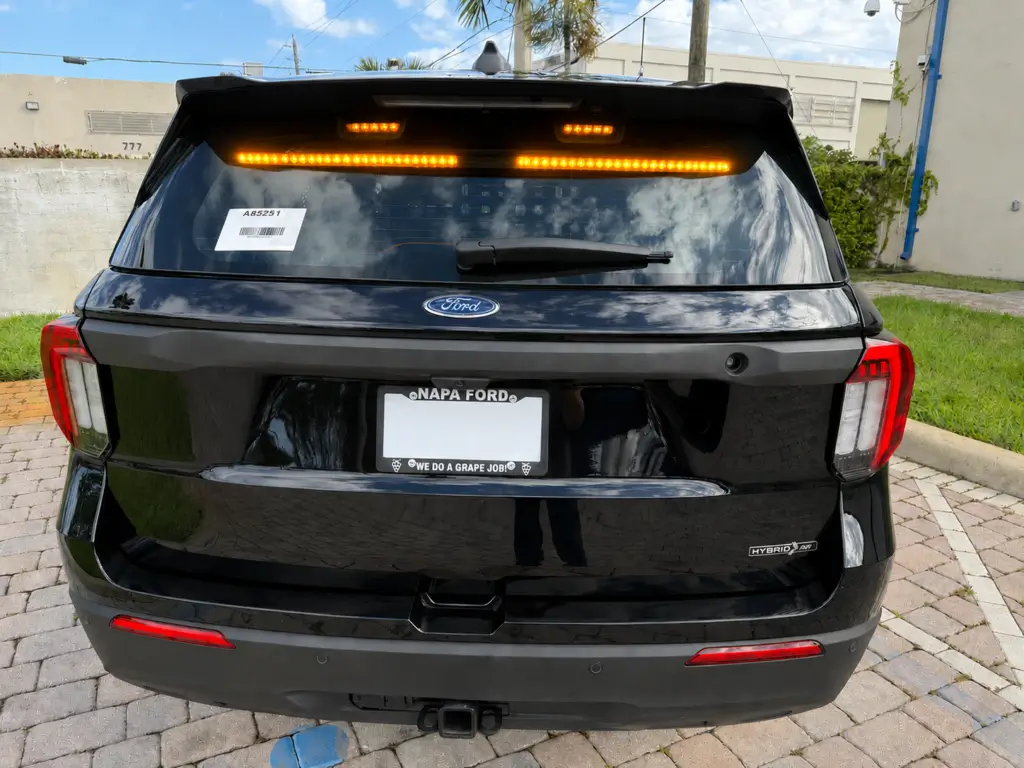 Rear view of a black Ford SUV equipped with an LED traffic advisor and directional warning bar displaying flashing amber lights, designed to improve traffic control, roadside safety, and fleet vehicle visibility.