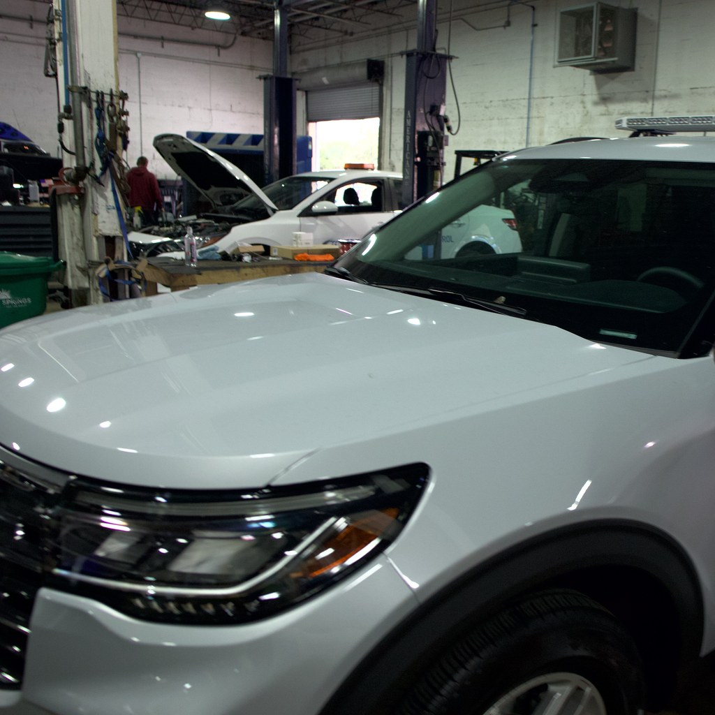 Unmarked white Ford Explorer with a roof light bar in the OCM Upfitting shop